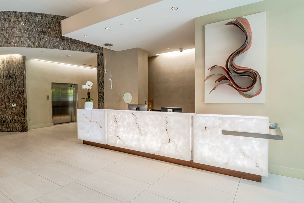 a reception desk in a hotel lobby with a painting on the wall